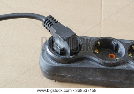 Used Electric Extension Cord On A Beige Background. Black Developer With A Plug In The Plug. Electri