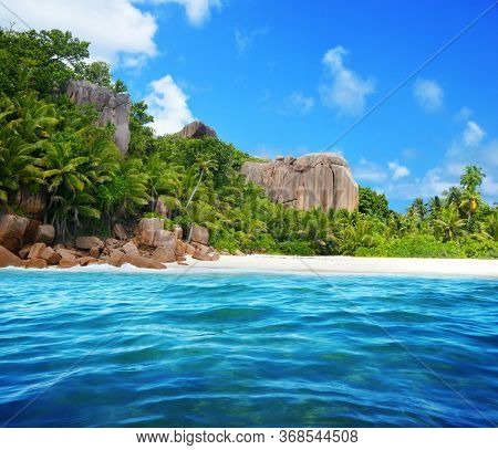 Granite rocks and coconut palm trees on sand beach of the island Grande Soeur near La Digue, Indian Ocean, Seychelles.