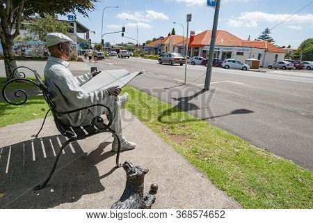 Katikati New Zealand - January 6 2014 - Bronze Statue Of Man Sitting On Park Bench Reading Newspaper