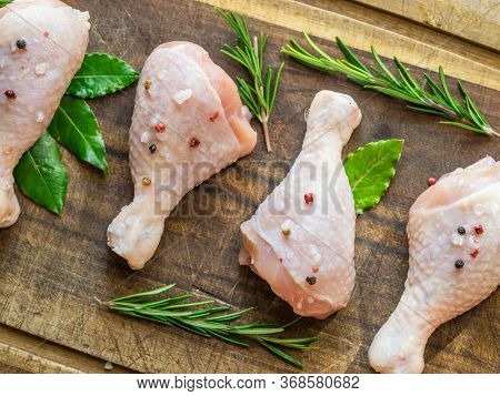 Chicken legs with spices and salt  ready for cooking on cutting board.