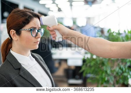 Temperature Measurement By Electronic Infrared Thermometer For Office Staff. Unhappy Woman With A Fe