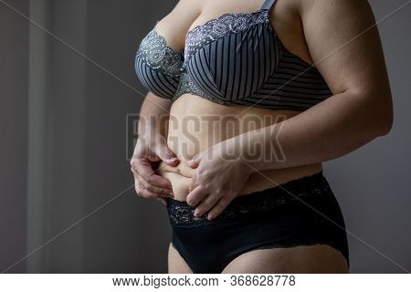 Woman Real Body Plus size Model in lingerie posign and touching fat on stomach, imperfect nonideal