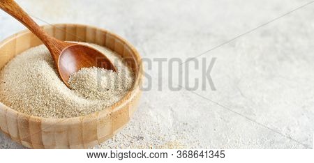 Raw Fonio Seeds In A Bowl With A Spoon On White Background Close Up. Alternative Flour