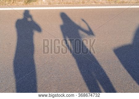 Shadows And Silhouettes Of People At A City During Sunset. Shadows Of The Family While Thay Was Runn