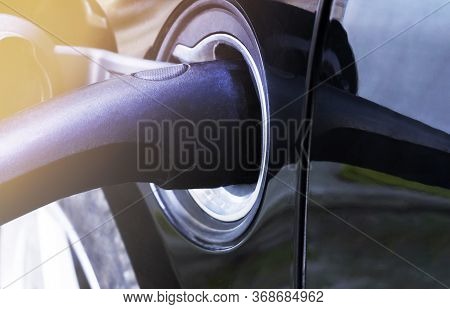 Power Cable In Electric Vehicle At Electro Charging Station. Luxury Black Auto Is Recharging. Enviro