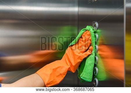 Woman Hand In Protective Orange Rubber Gloves Holding Green Microfiber Cleaning Cloth And Wiping Dus