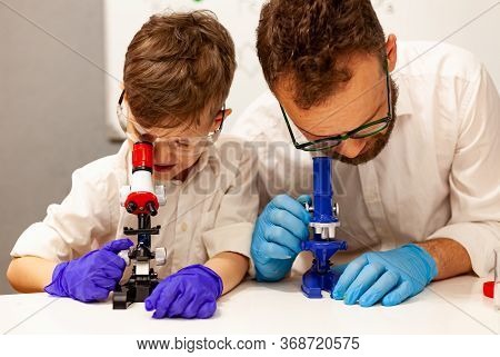 Dad And Son Play With A Microscope In A Makeshift Laboratory