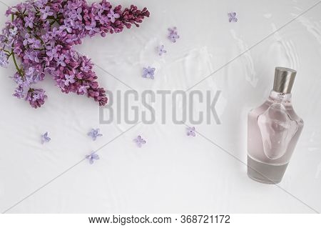 Glass, Perfume, Cosmetic Bottle On White Background With Water And Lilac. Top View, Closeup.