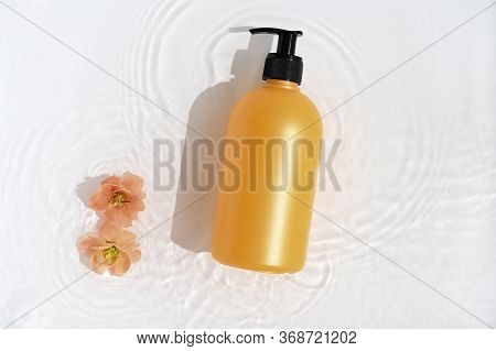 Cosmetic Bottle On White Background With Water And Flowers. Top View, Closeup