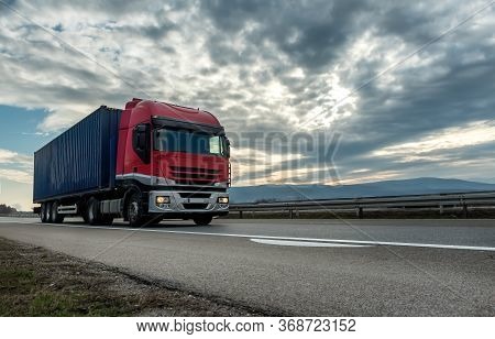 Red Transportation Semi Trailer Truck On A Highway Driving At Bright Sunny Sunset. 

Transportation 