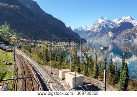 Railway Along The Shore Of Lake Lucerne Near The Town Sisikon. View Of The Snow-covered Alps. Canton