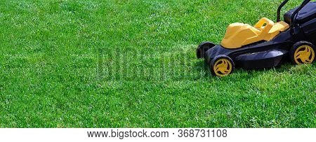 Electric Yellow And Black Lawnmower On Green Grass, Copy Space