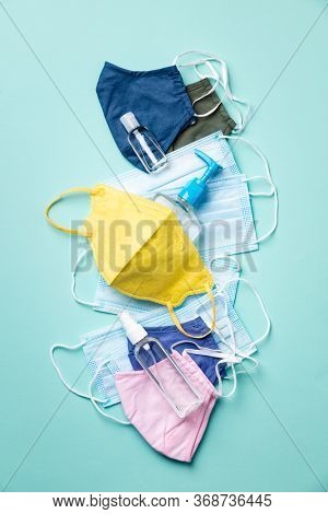 Various Face masks for protection virus, flu, coronavirus, COVID-19. Medical masks, cotton reusable masks and hand sanitizers on blue background. Flat lay, top view