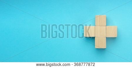 Wooden Blocks In The Form Of A Cross On Blue Background. Success, Medicine, Win, Victory, Developmen