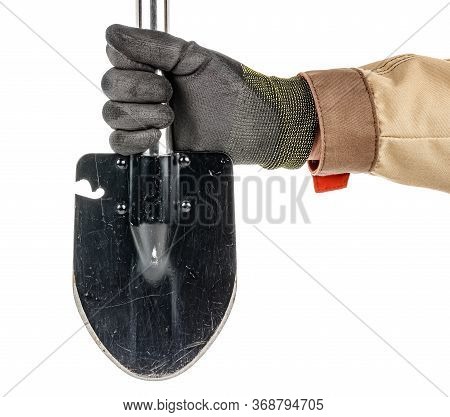 Man Hand In Black Protective Glove And Brown Uniform Holding Black Folding Shovel With With Scratche
