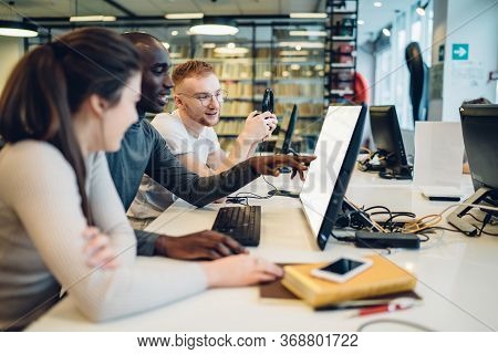 Interested Multiracial Students Using Computer While Studying In Library
