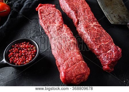 Raw Marbled Beef Steak Near Butcher Knife With Pink Pepper And Rosemary. Black Background. Side View
