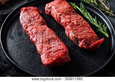 Raw Denver Cut Black Angus Organic Steak On A Black Plate And Stone Slate With Seasonings, Herbs Gre