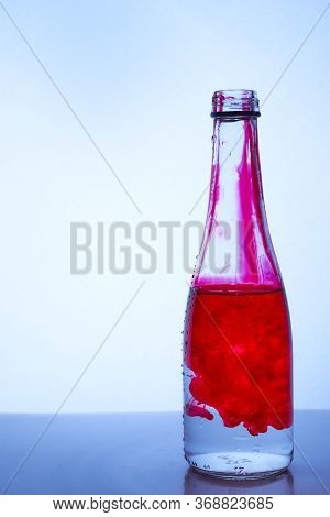 Red Ink Mixed With Water In A Glass Bottle On A Light Background