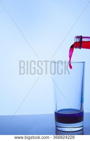 Red Wine Is Poured Into A Glass Glass With Blue Liquid