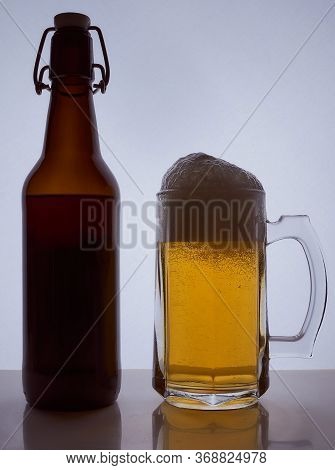 Colored Silhouette Of A Beer Bottle With A Cork And Beer Mug With Beer Poured Into It On A Black Whi