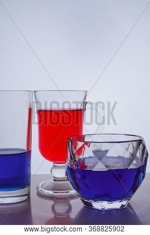 Composition Of Different Glass Glasses On A White Background With Multicolored Liquids