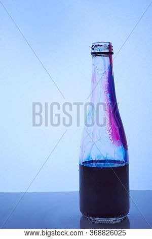 A Blue Liquid Is Poured Into A Glass Bottle. Light Blue Background