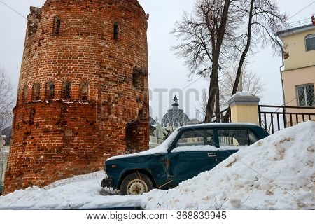 An Old Passenger Car Stands In A Snowdrift Near The Old Fortress Tower