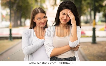 Fake Friendship Concept. Gloating Girl Rejoicing At The Misfortune Of Crying Female Friend Standing 