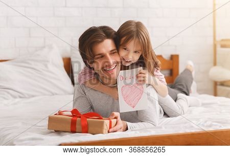 Lovely Preschool Girl Greeting Her Happy Daddy With Father Day, Giving Him Gift Box And Greeting Car