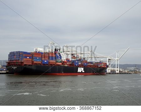 Oakland - April 21, 2011: Apl Shipping Line Shipping Boat Is Unloaded By Cranes In Oakland Harbor On