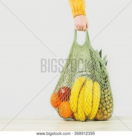 Delivery Of Grocery. Hand Holds Mesh Shoper Bag With Fresh Fruit And Vegetables Green Produce. Eco F