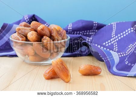 Group of dried sweet deglet nour date fruites in translucent bowl and dark violet napkin.Organic veg