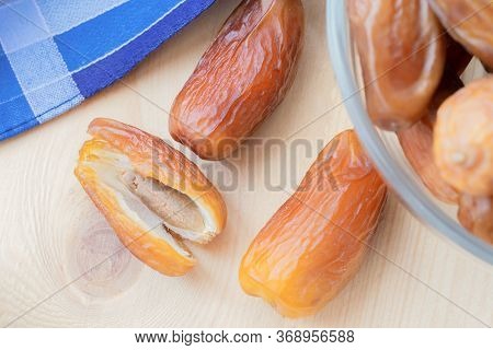 Group Of Dried Sweet Deglet Nour Date Fruites In Translucent Bowl And Dark Violet Napkin.organic Veg