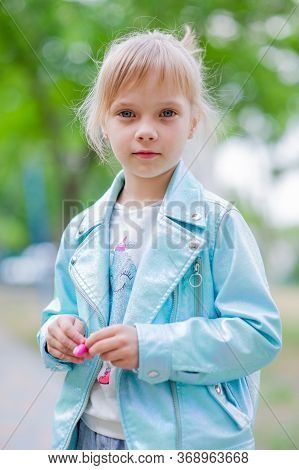 Close Up Portrait Of Young 6-7 Year Old Girl. Girl 7 Years Old Outdoors Portrait In A Blue Jacket. L