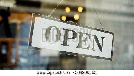 Close Up Of The Male Caucasian Hands Turning A Signboard On The Glass Door Of The Shop From Closed T
