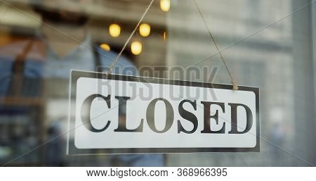 Close Up Of The Male Caucasian Hands Turning A Signboard On The Glass Door Of The Shop From Closed T
