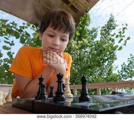 Child playing chess outdors, Young boy making a move.