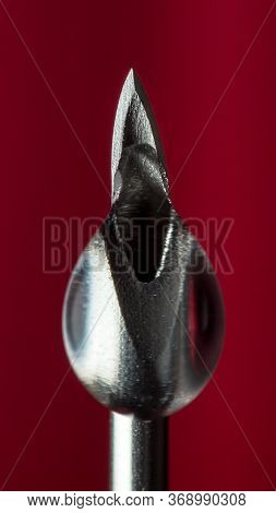 A Drop Of Clear Liquid, Drugs, Antibiotics, On The Tip Of The Needle Of An Injection Syringe, On A D