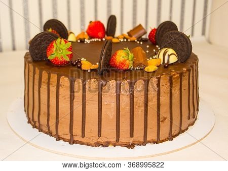 A Wonderful Sponge Cake Topped With Chocolate And Decorated With Cookies, Strawberries, Pieces Of Ch