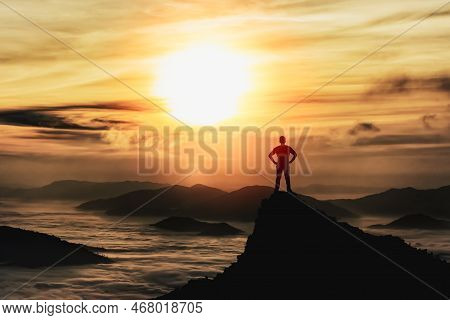 Silhouette Man Standing And Akimbo On Peak Of Stone Rock In Mountain And Watching To Sunrise Fog, Mi
