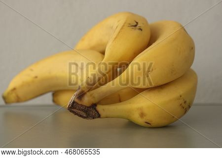 A Photograph Of Bananas Is Lying On A Grey Table, With The Focus On The Crown Of The Bananas, Which 