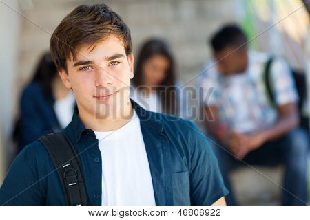 gut aussehende Highschool-Junge mit Freunden auf dem Hintergrund
