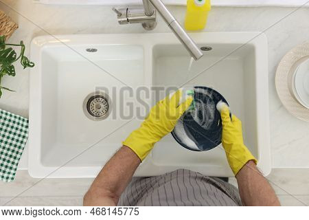 Man In Protective Gloves Washing Plate Above Sink Indoors, Top View