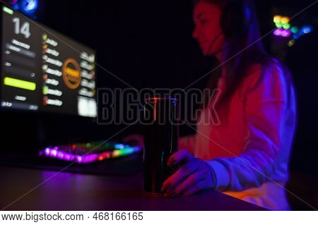 Young Girl Gamer Sits At A Computer And Drinks An Energy Drink, A Woman Plays In A Computer Club At 