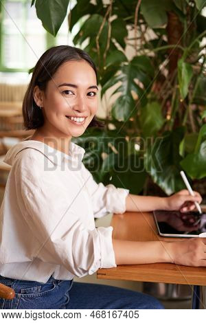 Vertical Shot Of Young Asian Woman With Digital Tablet And Graphic Pen, Drawing, Scratching While Si