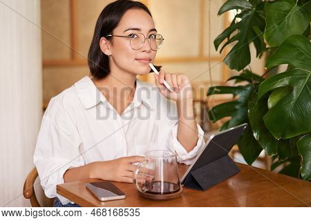 Young Artist Drawing On Digital Tablet, Using Graphic Pen, Drinking Coffee In Cafe And Scatching Smt