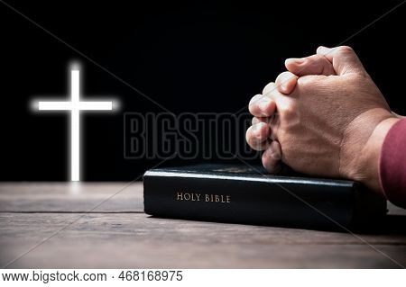 Hands Folded In Prayer On Holy Bible With Cross In Church Concept For Faith, Spirituality And Religi