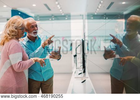 Seniors shopping appliences and gadgets in tech store.