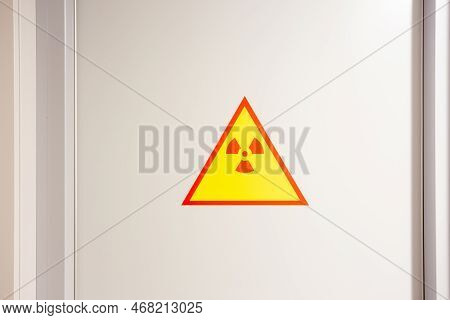 Red And Yellow Radiation Precaution Sign On The White Steel Wall.